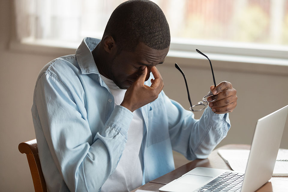 African guy sit near laptop taking off glasses reduce eyestrain